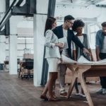 Group of young business people working together in creative office while standing near the wooden desk